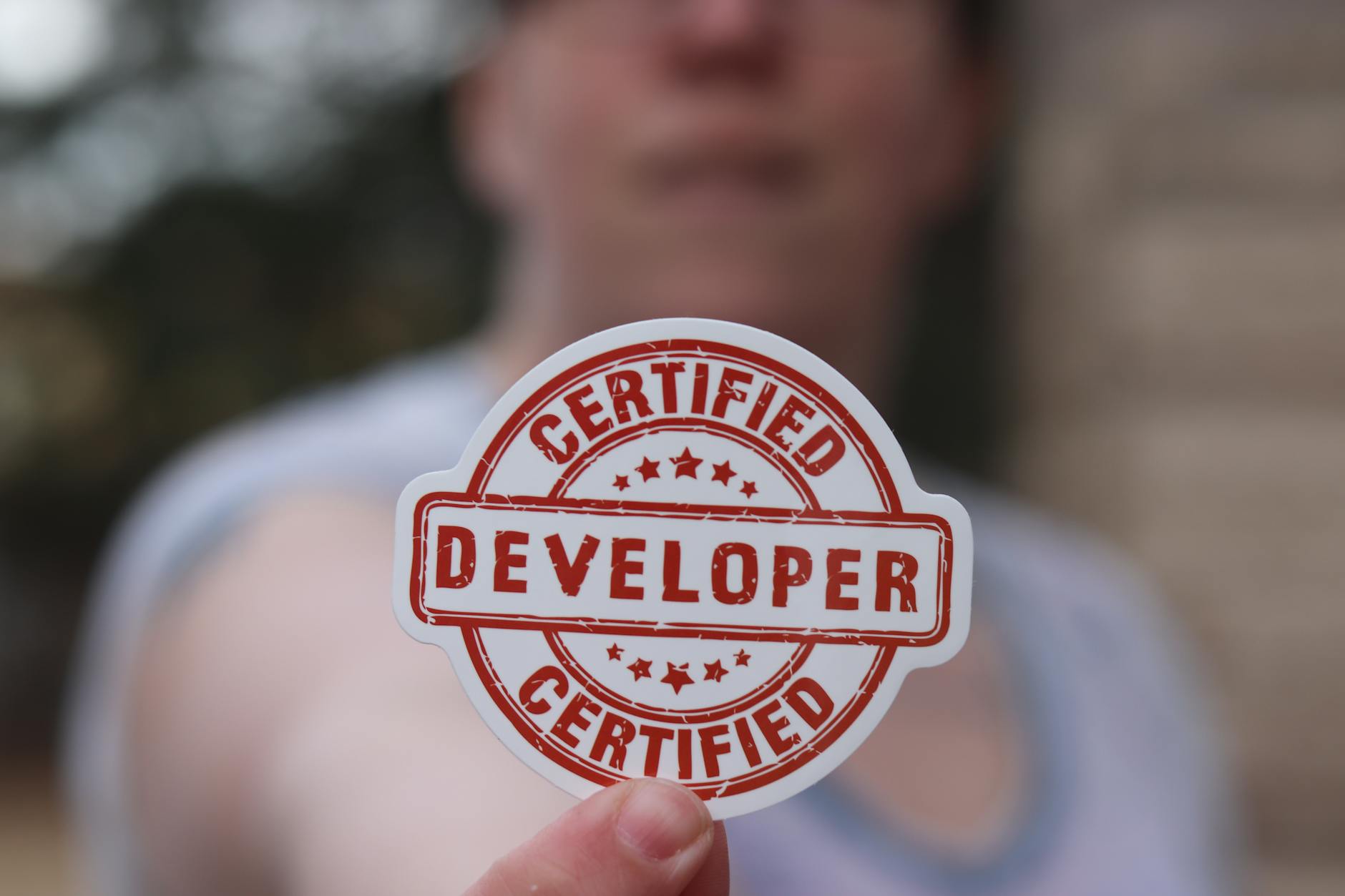 software developer certification with finger holding badge